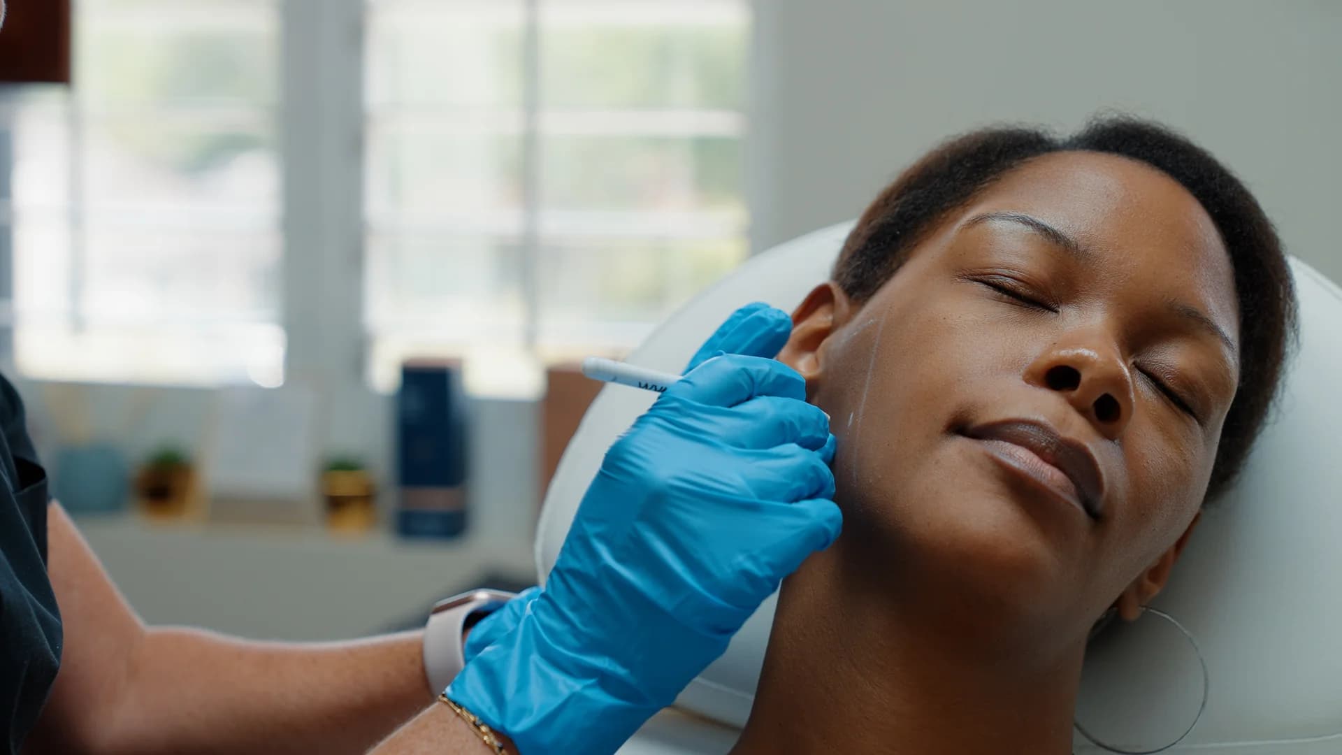 A provider marking a client's jaw area during an assessment at Greene Emerald Med Spa