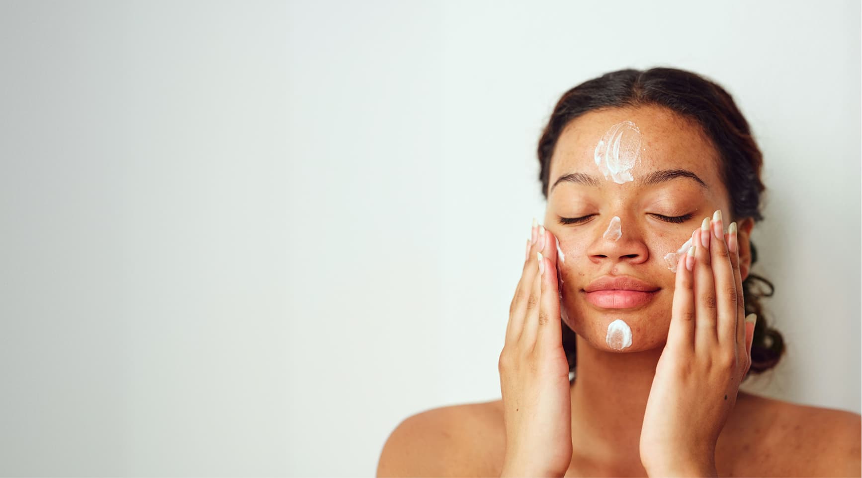A woman applying skincare to her cheeks