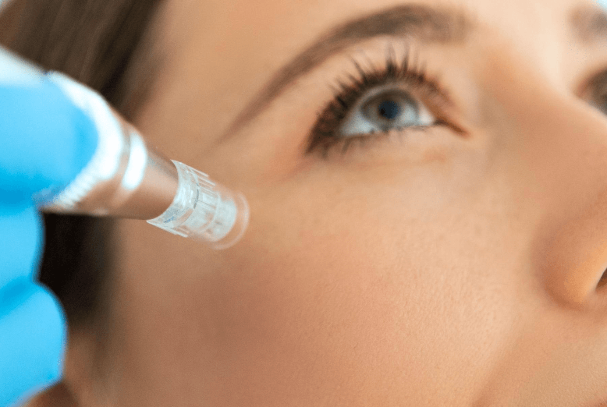 Close-up of a person receiving an eyebrow grooming treatment by a professional wearing black gloves.